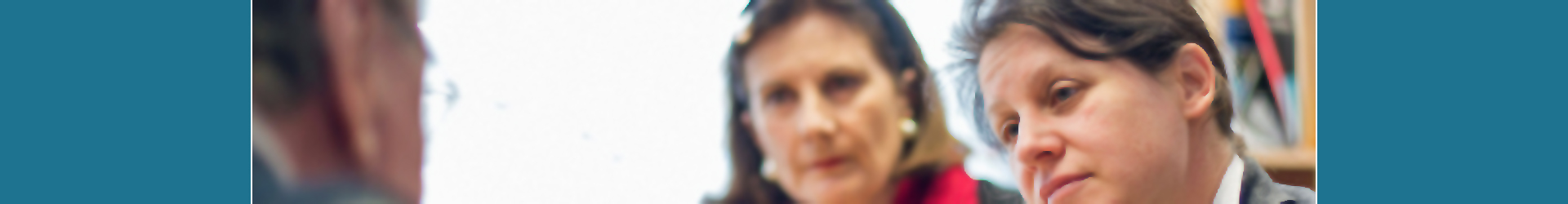 Zwei Ärztinnen sitzen mit einem Patienten in einem Beratungsgespräch.